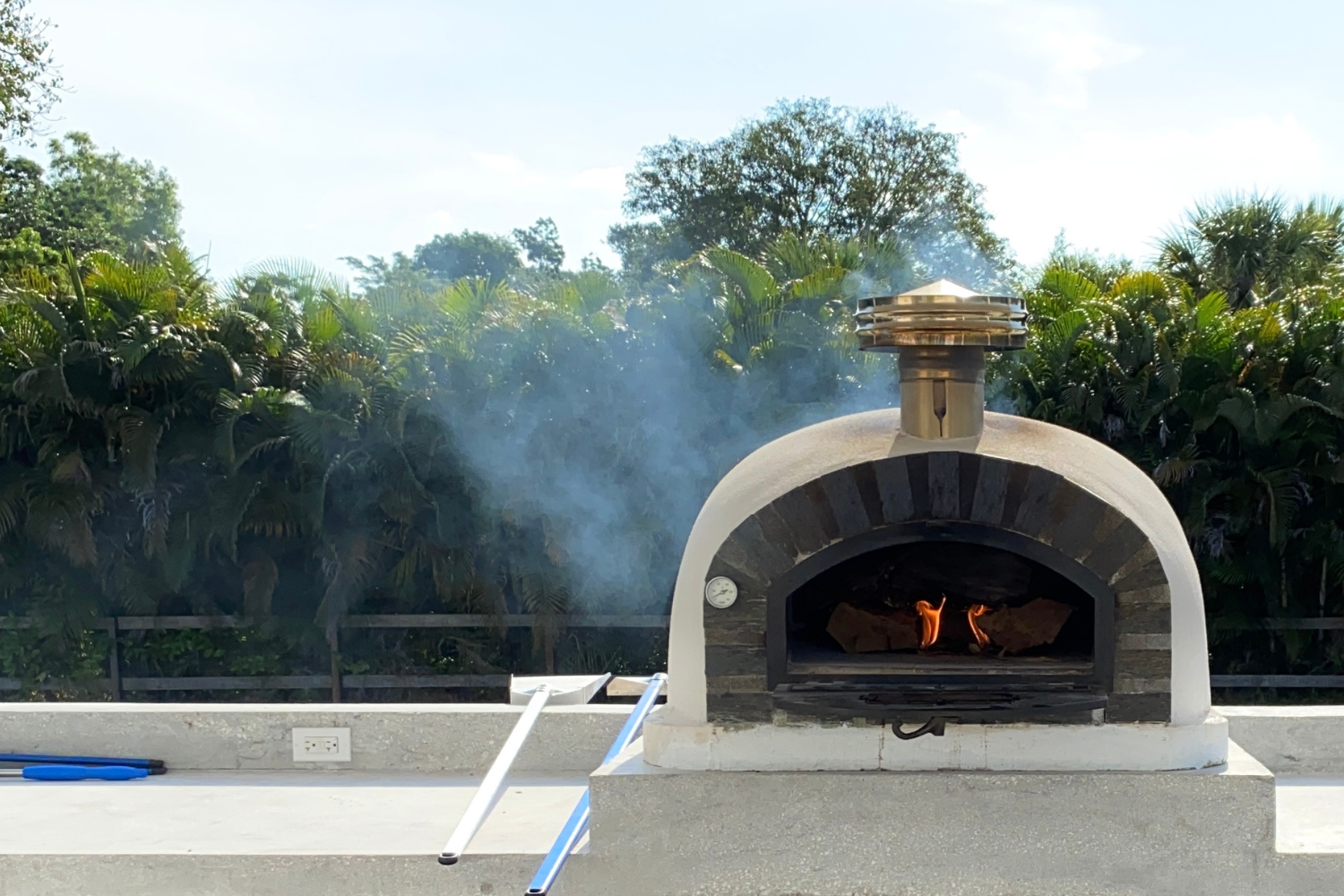 Authentic Pizza Ovens Pizzaiolo Stone Arch Premium with wood fire burning, pizza door open down in an outdoor area